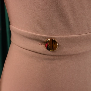Detailed close-up of a golden round button on a pinkish-brown knitted dress waist
