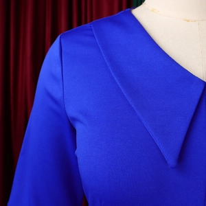 Dettaglio del colletto asimmetrico sovrapposto su vestito in maglia blu reale