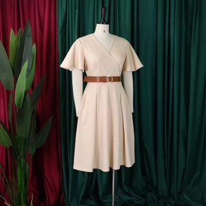Detail of V-neck beige dress with flared sleeves and a brown leather waist belt