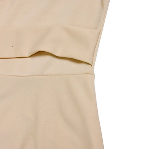 Detail of beige knitted dress showing hollow waist cutout and fine fabric texture