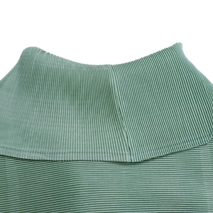 Dettaglio ravvicinato della camicetta verde chiaro a pieghe con collo alto e texture
