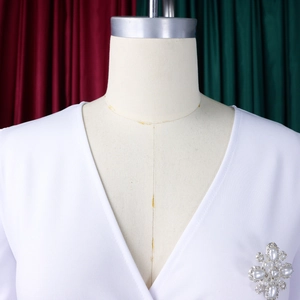 Detail der eleganten Perlen- und Strassblumenbrosche auf einem weißen Kleid mit V-Ausschnitt