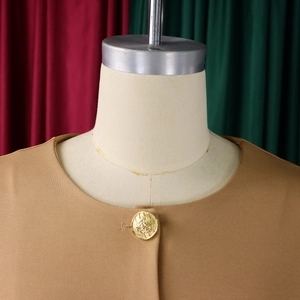 Close-up of golden embossed button and elegant neckline on a camel colored textured suit