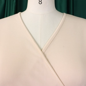 Close-up of beige wrap V-neckline with fine stitching on an elegant A-line dress