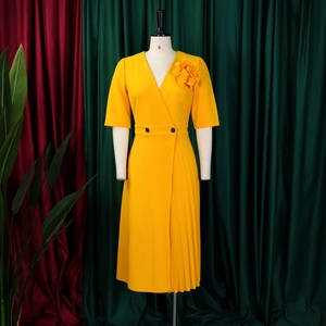 Detailed view of yellow V-neck dress featuring 3D flower shoulder and pleated hem
