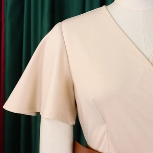 Close-up of elegant V-neckline and ruffled short sleeves on apricot maxi dress