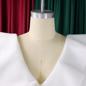 Detail of white V-neck dress featuring structured ruffles and architectural pleats