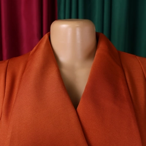 Detailed close-up of orange suit jacket lapel with textured fabric on a mannequin