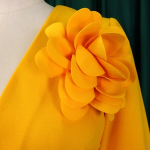 Close-up of bright yellow pleated dress featuring elegant 3D floral shoulder detail