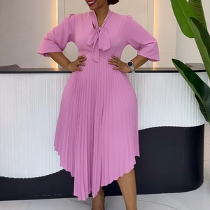 Detail of elegant pink dress featuring a bow tie neckline and pleated asymmetrical hem
