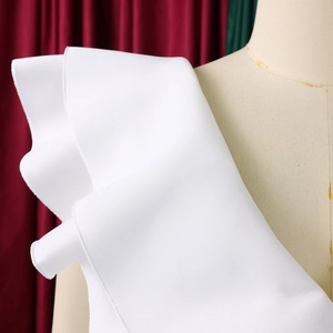 Detail shot of elegant white ruffled layers and smooth fabric texture on the shoulder