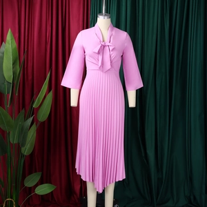Detail of elegant V-neckline with a bow tie and pleated hem on a light pink dress