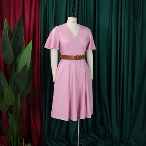 Close-up of pink V-neck dress with brown leather belt on mannequin in a studio setting