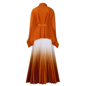 Dettaglio del top in maglia arancione con lacci e gonna a pieghe sfumata elegante