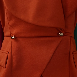 Detailed view of burnt orange dress with waist fold design and gold metal buttons