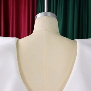 Detail view of bold padded shoulder design on a white V-neck evening gown for women