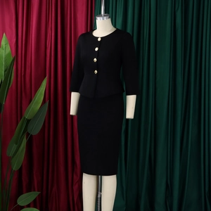 Close-up of black business suit set featuring gold buttons and elegant ruffle hem detail
