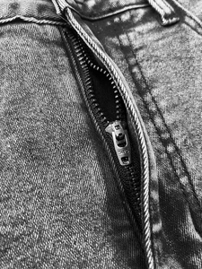 Detail of high-quality SBS brand metal zipper on floral embroidered denim jeans