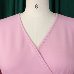 Close-up of pink V-neck dress featuring textured horizontal knit and precise stitching