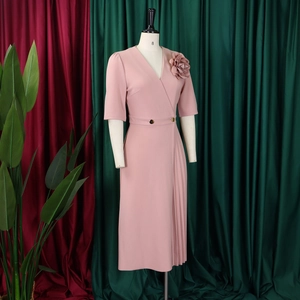 Detail of pink V-neck dress featuring 3D floral accents and pleated side skirt