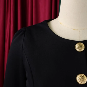 Detail of elegant round neck black suit with decorative gold crest buttons and ruffle sleeves