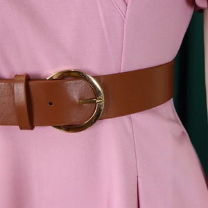 Detail of pink dress waist featuring a brown faux leather belt with a round gold buckle