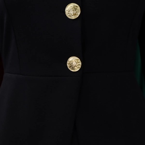 Close-up of elegant black blazer featuring embossed gold Medusa-style buttons