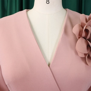 Detail of elegant V-neck dress featuring a large 3D pleated fabric flower on shoulder