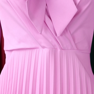 Detail of elegant pink pleated dress showing cross V-neckline and refined fabric texture