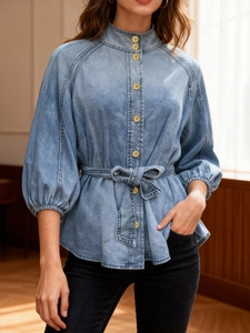 Detail view of retro denim shirt featuring high collar and lantern sleeves with waist tie