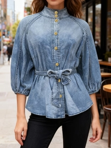 Detail of light blue denim shirt with lace-up waist, lantern sleeves and metal buttons