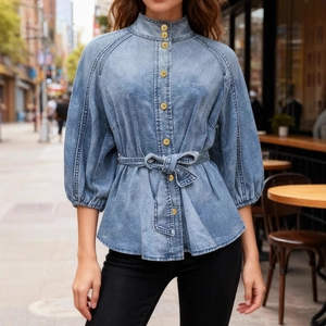 Detail of light blue denim shirt featuring lantern sleeves and gold buttons with tie waist