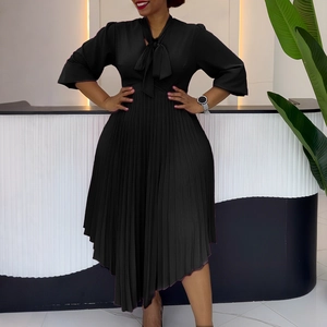 Detail of elegant black dress showing bow neckline and pleated asymmetrical hemline
