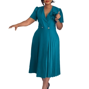 Detail of teal V-neck dress featuring floral shoulder decor and pleated skirt elements