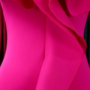 Close-up detail of hot pink dress showing ruffle design and precision stitching