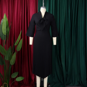 Close-up of elegant black pleated midi dress with bow tie neckline and 3/4 sleeves