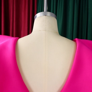 Detail of rose pink satin dress featuring structured padded shoulders and deep V-neckline