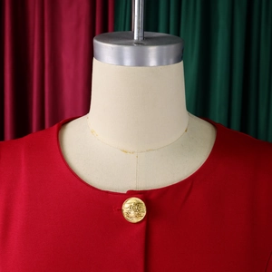 Detail of red crewneck suit with decorative gold embossed crest button and fine texture