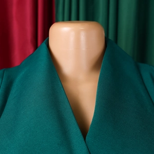 Close-up detail of dark green suit collar with premium twill texture and V-neckline
