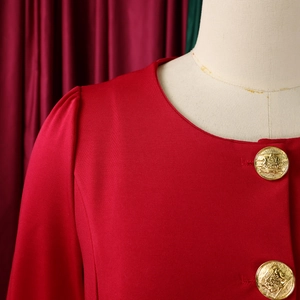 Detailed close-up of golden embossed crest buttons on a red ruffled sleeve jacket