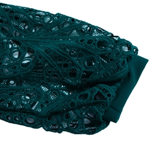 Detailed macro view of dark green hollow lace fabric and intricate embroidery on dress cuffs
