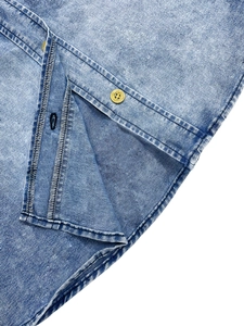 Close-up of light blue denim shirt showing high-quality buttons and washed fabric texture