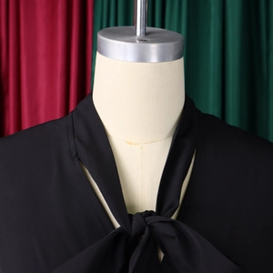 Detail of elegant black dress with self-tie bow neckline and smooth chiffon fabric