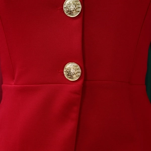 Detail of red blazer fabric with horizontal texture and golden lion head buttons