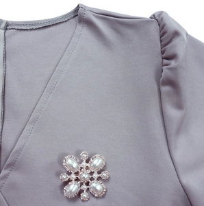 Nahaufnahme des fliederfarbenen V-Ausschnitt-Kleides mit feiner Perlen-Strass-Brosche