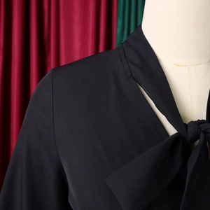 Close-up of elegant V-neckline with a delicate bow tie on a black pleated dress