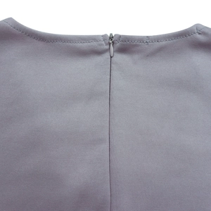 Detail des V-Ausschnitts mit verdecktem Reißverschluss und feinen Nähten am grauen Kleid
