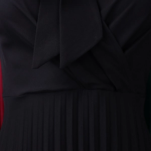 Detail of elegant black V-neck dress with bow tie collar and fine pleated fabric texture