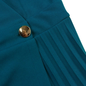 Detail of teal pleated fabric showing elegant texture and a round gold metallic button