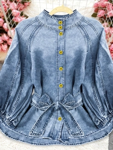 Detail of light blue denim shirt featuring yellow buttons and a waist bow tie design